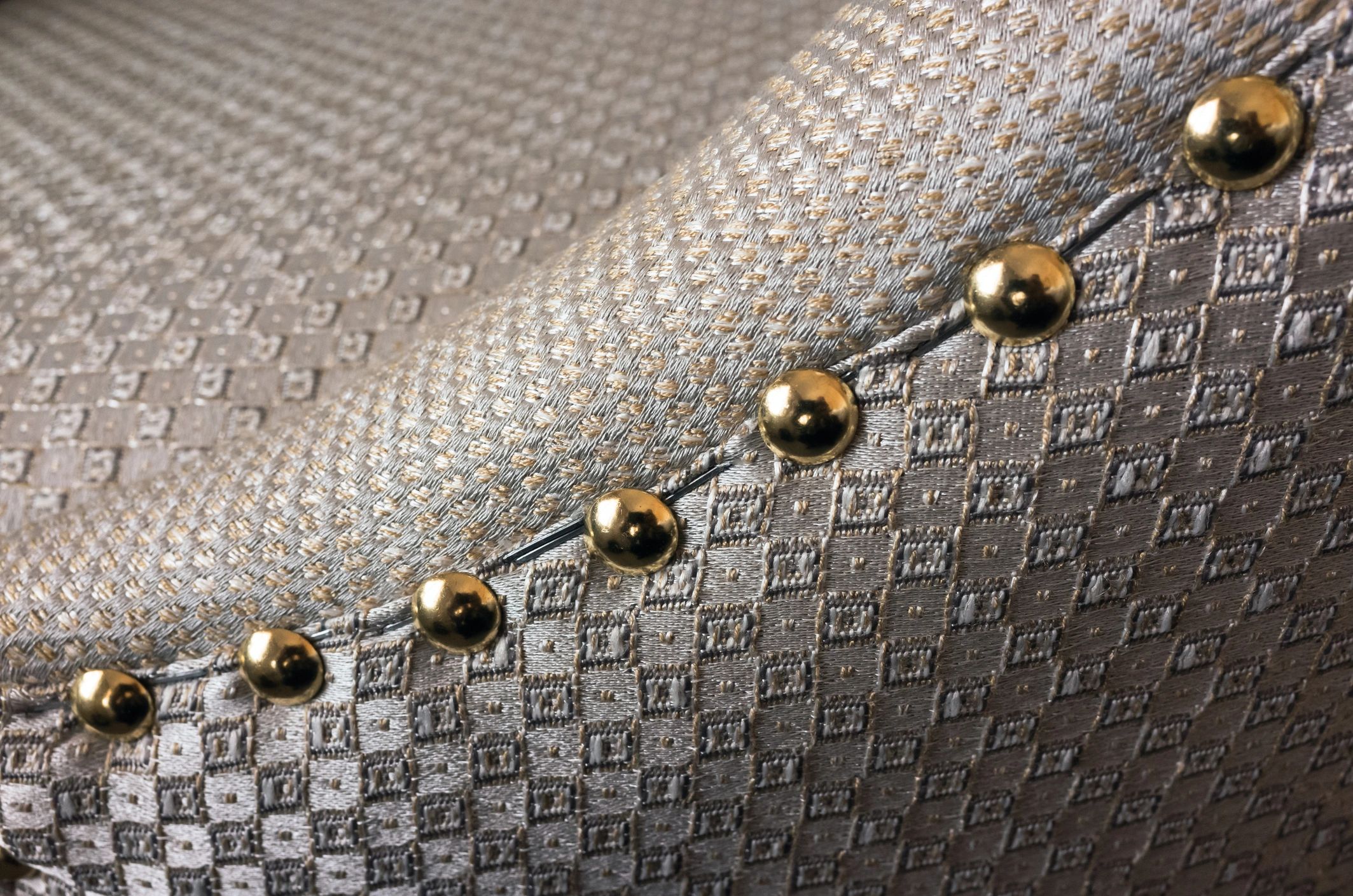Close-up of a reupholstered vintage armchair with nailhead trim